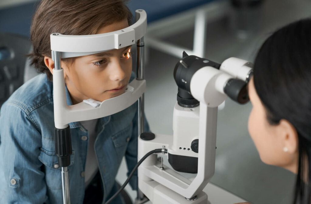 An optometrist performing a slit-lamp exam on a child to detect eye problems.