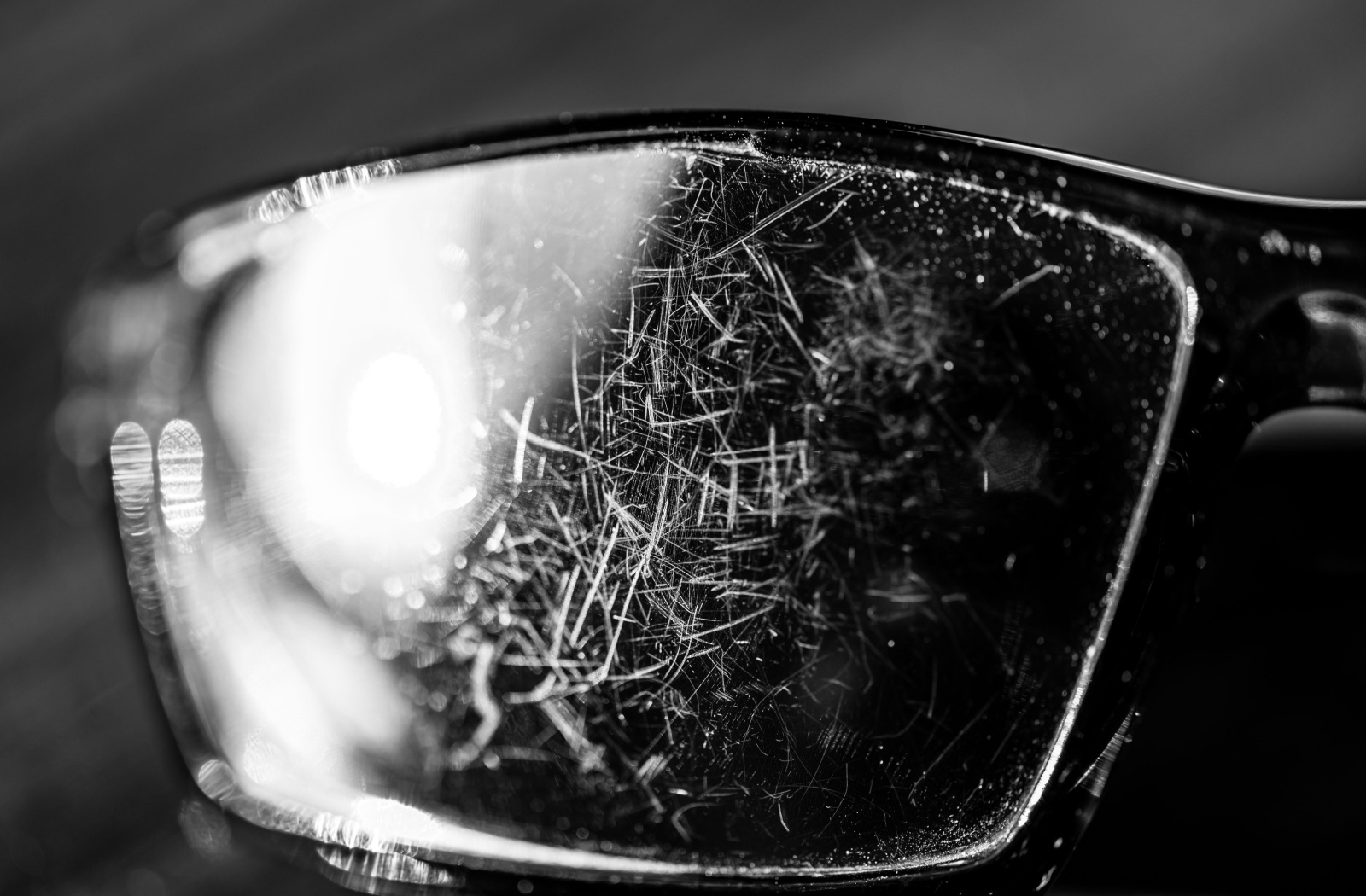 A close-up of eyeglasses lens covered in scratches.