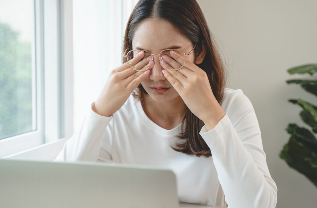 A person with dry eyes pushes their glasses aside and rubs their eyes.