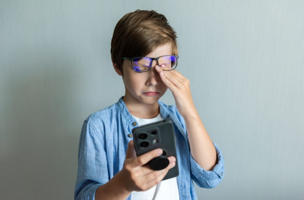 A child rubbing their eye after looking at a phone for too long