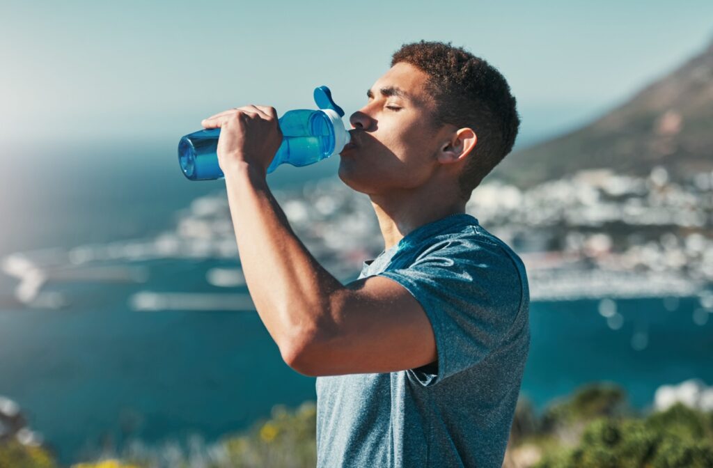 Someone hydrating by drinking from a water bottle.