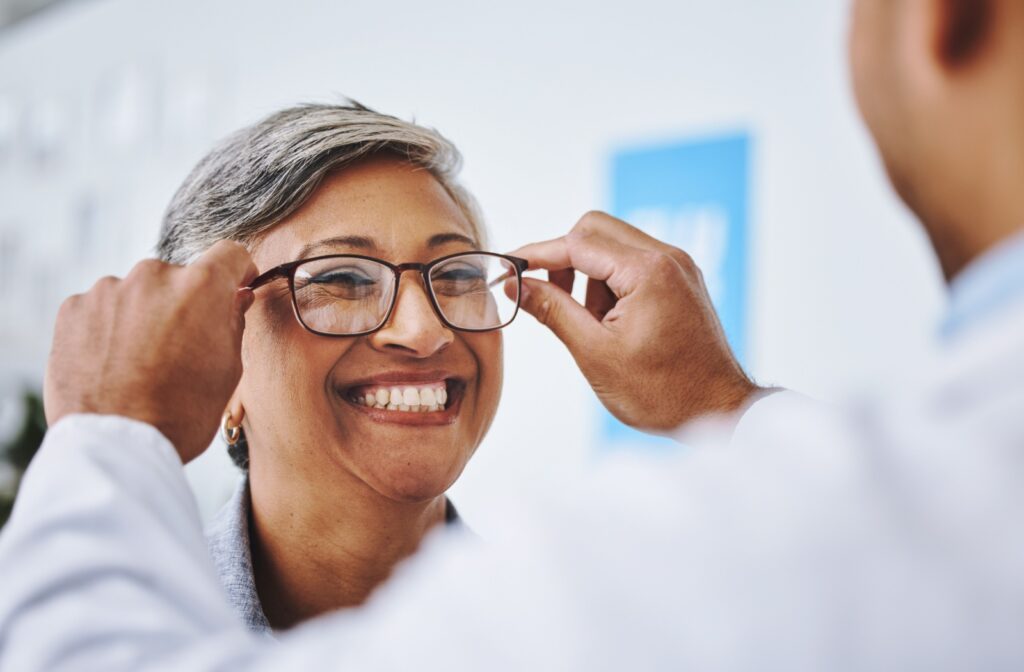 A woman smiles as she tries on a new pair of glasses at the optometrist