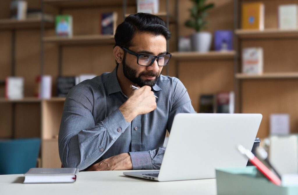 A person wearing glasses looks at a computer screen while working