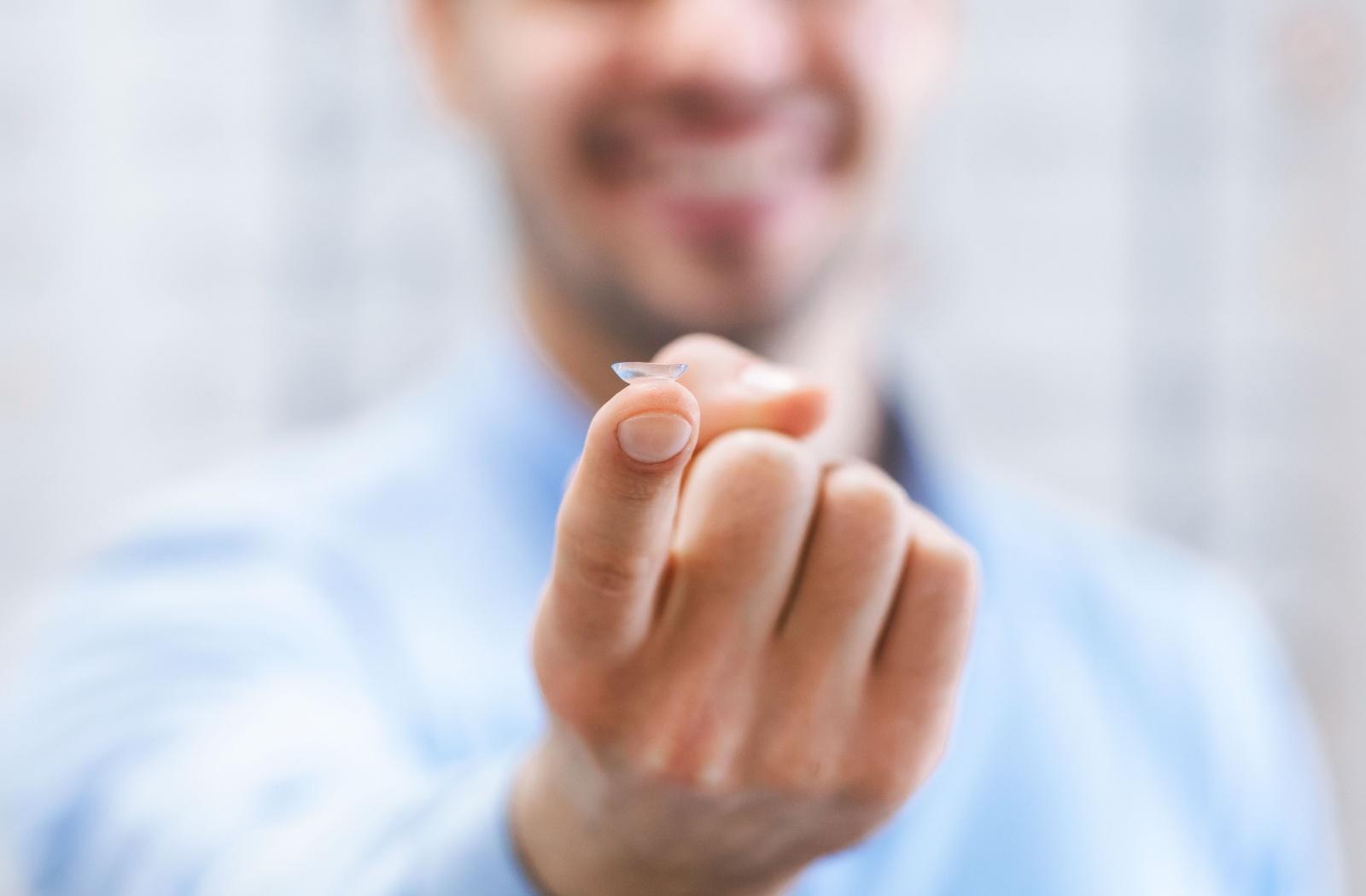 A person holding a single contact lens on the tip of their finger
